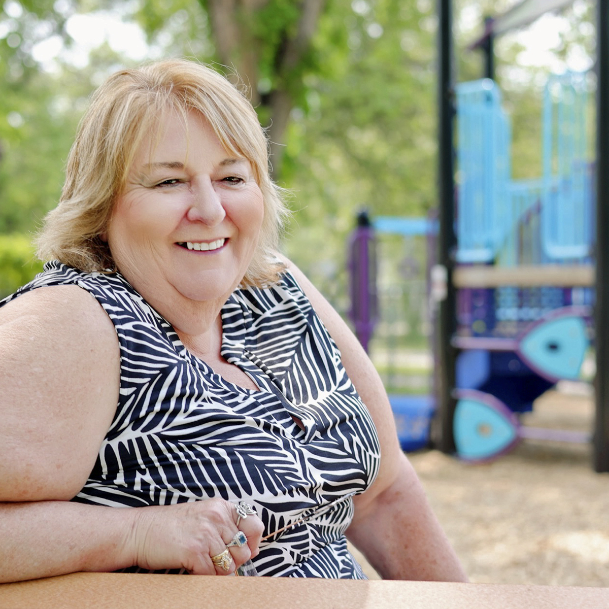 Debbie Rusk, the proud representative of Blue Imp playground equipment for Manitoba since 1997. She is pictured smiling, conveying her dedication and experience in helping schools, municipalities, daycares, and Indigenous communities create safe and exciting playground spaces across Manitoba.